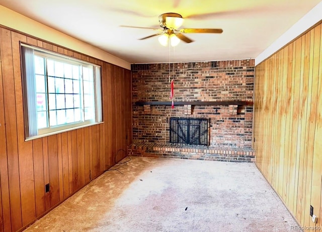 unfurnished living room featuring a brick fireplace, carpet, and wooden walls