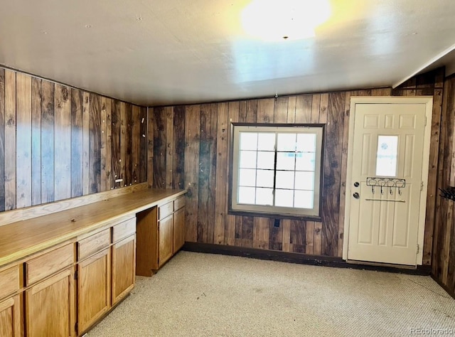 kitchen with wood walls, vaulted ceiling, brown cabinetry, and light countertops