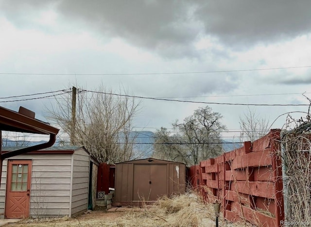 view of yard with fence, a storage unit, and an outdoor structure