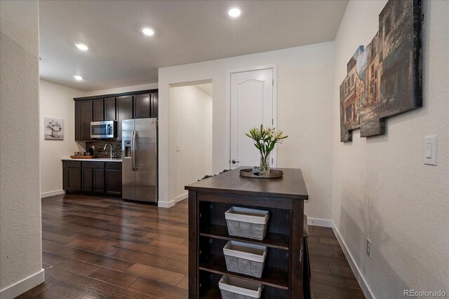 kitchen featuring dark brown cabinets, appliances with stainless steel finishes, dark wood-type flooring, and baseboards