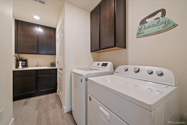 washroom with separate washer and dryer, wood finish floors, a sink, and cabinet space