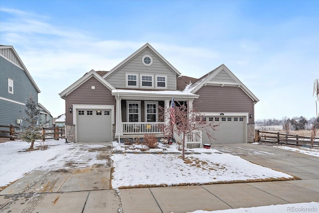 view of front of home featuring stone siding, covered porch, a garage, and fence