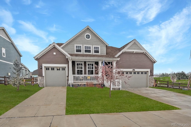 craftsman house with fence, covered porch, stone siding, a front yard, and driveway