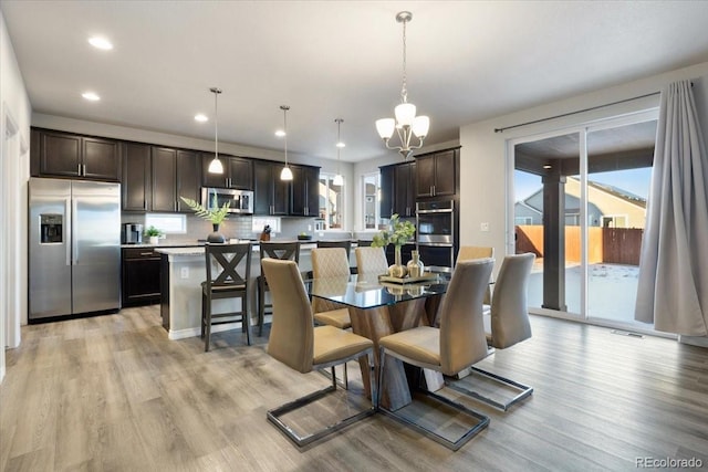 dining area with light hardwood / wood-style floors and a notable chandelier