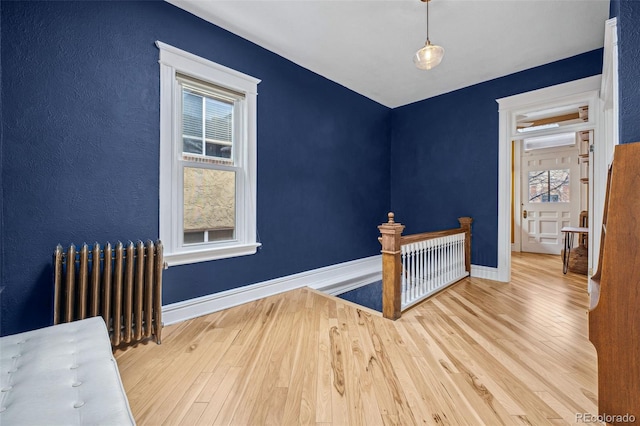 interior space with radiator heating unit, wood finished floors, and baseboards