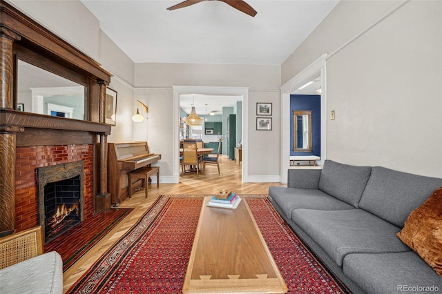 living room featuring a fireplace, visible vents, a ceiling fan, wood finished floors, and baseboards