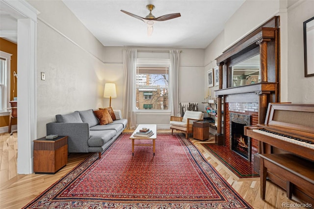 living room featuring a brick fireplace, a ceiling fan, and wood finished floors