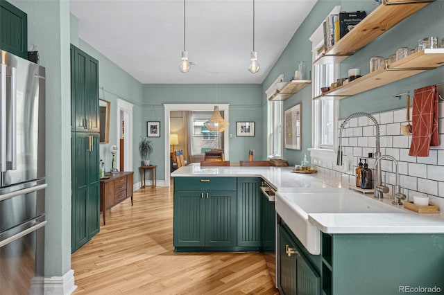 kitchen with green cabinets, freestanding refrigerator, a peninsula, light wood-type flooring, and open shelves