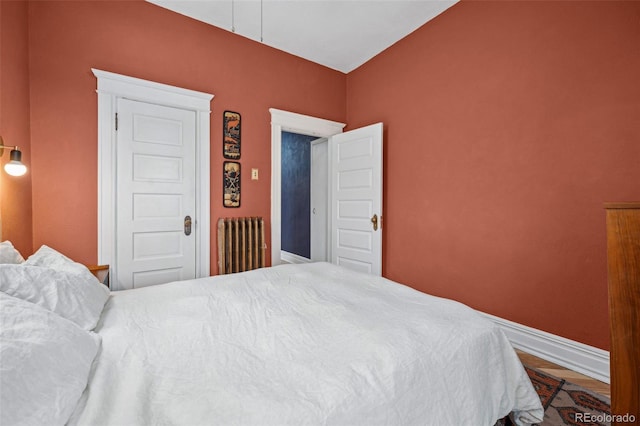 bedroom featuring baseboards, wood finished floors, and radiator