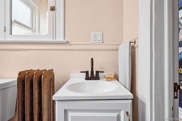 bathroom with a textured wall and vanity