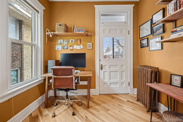 office area featuring radiator heating unit, wood finished floors, and baseboards