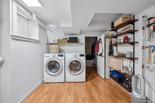 clothes washing area featuring washer and dryer, light wood-type flooring, laundry area, and baseboards