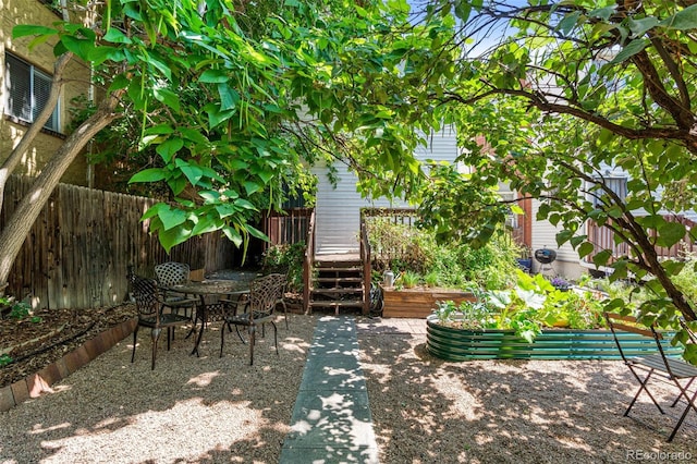 view of patio featuring a garden, fence, and a deck