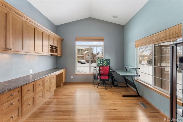 office area featuring light hardwood / wood-style floors, vaulted ceiling, and a healthy amount of sunlight