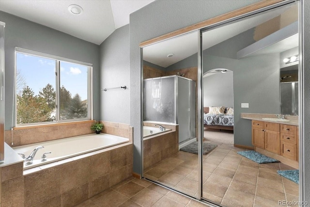 bathroom featuring independent shower and bath, lofted ceiling, and vanity