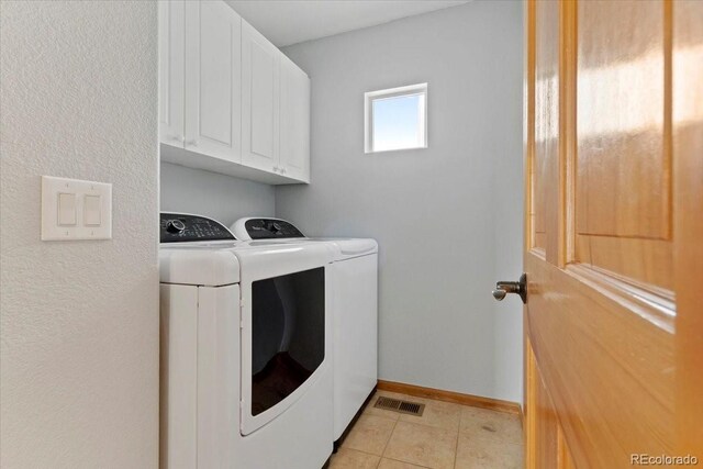 clothes washing area with cabinets, light tile patterned floors, and washing machine and dryer