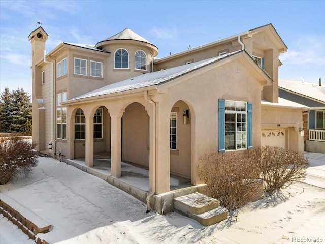 view of front facade featuring stucco siding, an attached garage, and a chimney