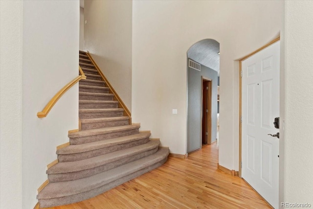 foyer entrance featuring visible vents, baseboards, stairway, and light wood finished floors