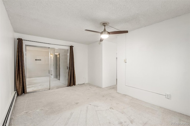 carpeted spare room featuring a baseboard heating unit, a textured ceiling, and ceiling fan