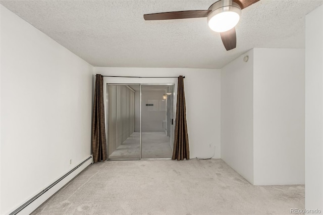 spare room featuring a textured ceiling, light colored carpet, ceiling fan, and baseboard heating