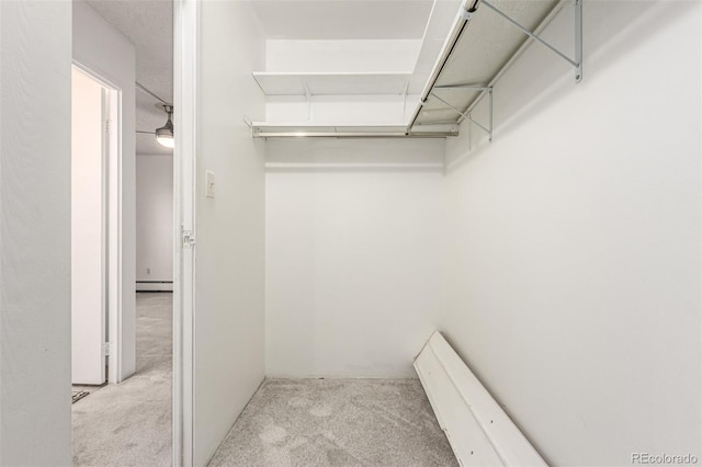 spacious closet featuring baseboard heating and light colored carpet