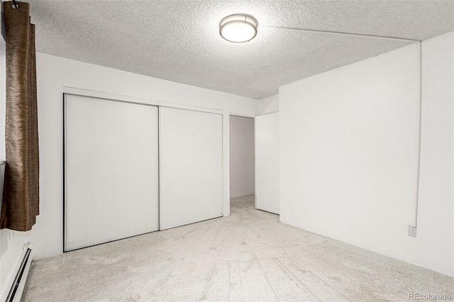 unfurnished bedroom with light carpet, a closet, a textured ceiling, and baseboard heating