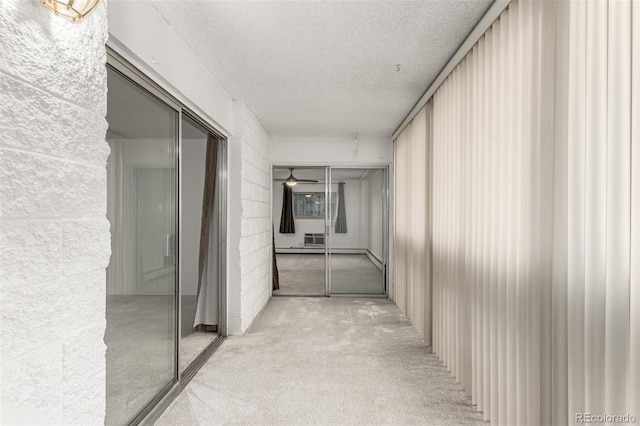 hallway with light colored carpet and a textured ceiling