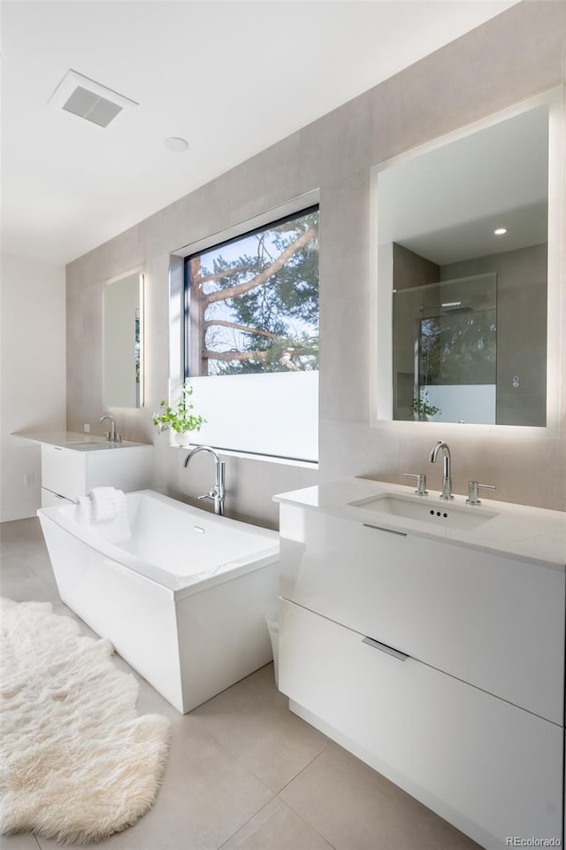 bathroom with vanity, tile patterned floors, shower with separate bathtub, and tile walls