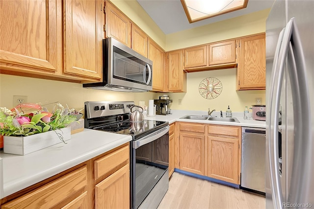 kitchen featuring sink, stainless steel appliances, light wood-type flooring, and light brown cabinetry