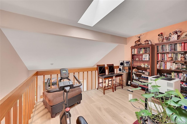 home office with light hardwood / wood-style floors and lofted ceiling with skylight