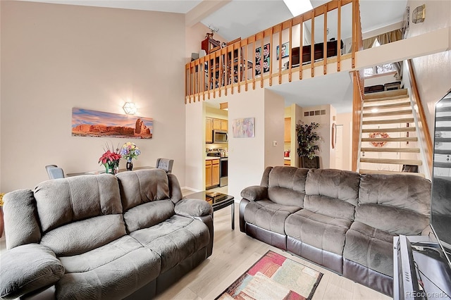 living room with high vaulted ceiling, light hardwood / wood-style flooring, and beamed ceiling