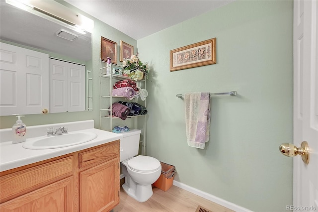 bathroom with toilet, hardwood / wood-style flooring, a textured ceiling, and vanity