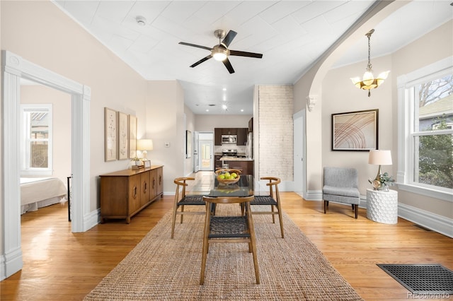 dining space with plenty of natural light, visible vents, light wood-style flooring, and arched walkways