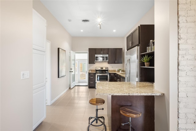 kitchen with stainless steel appliances, visible vents, dark brown cabinets, a peninsula, and a kitchen bar