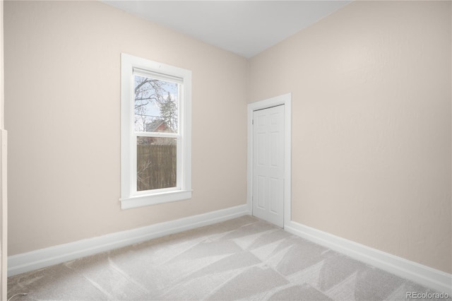 spare room with light colored carpet and baseboards