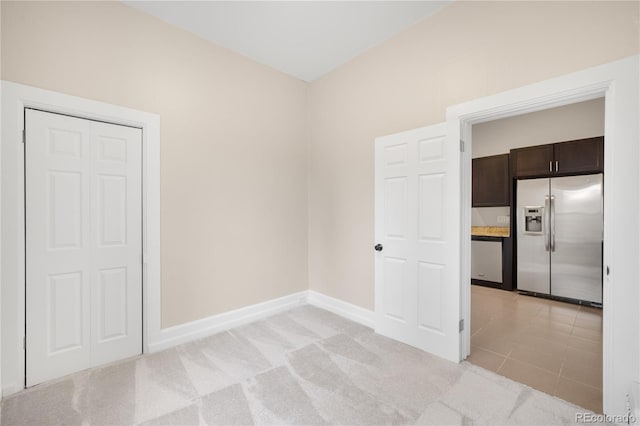 unfurnished room featuring light carpet and baseboards