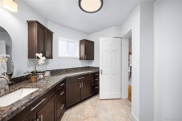 kitchen featuring dark stone counters, a sink, and dark brown cabinetry