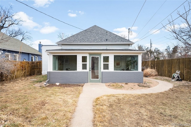 view of front facade with a shingled roof, a fenced backyard, and a front lawn