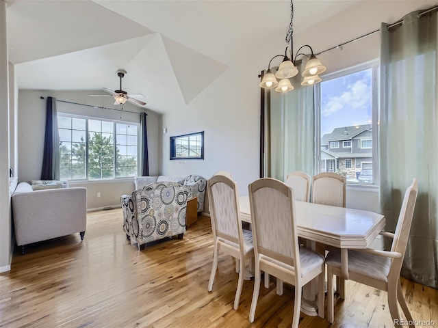 dining area with ceiling fan with notable chandelier, vaulted ceiling, and light wood-type flooring