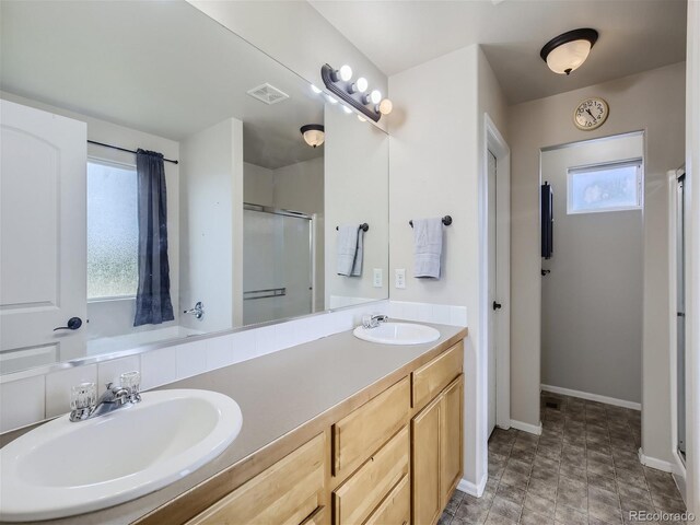 bathroom with double vanity, tile floors, and a shower with door