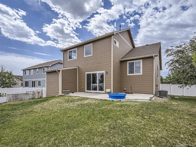 rear view of property with a patio, a yard, and central AC