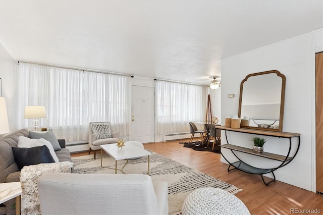 living room featuring a baseboard radiator, wood finished floors, and a ceiling fan