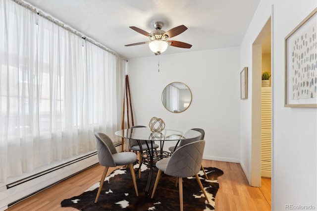 dining room with light wood-style flooring, a baseboard heating unit, and ceiling fan