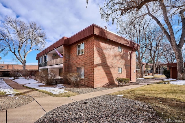 view of side of property with a balcony and brick siding