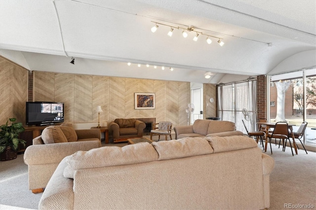 living room featuring wooden walls, a fireplace, lofted ceiling, carpet floors, and a textured ceiling