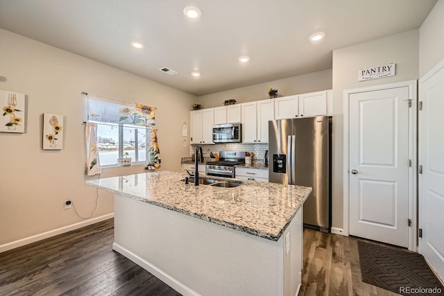 kitchen featuring sink, white cabinets, a kitchen island with sink, light stone counters, and stainless steel appliances