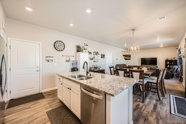 kitchen featuring white cabinetry, sink, hanging light fixtures, stainless steel dishwasher, and a center island with sink