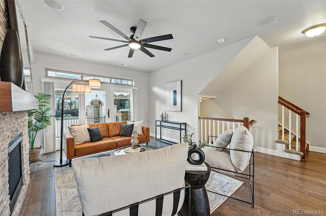 living area featuring a fireplace, wood-type flooring, baseboards, and ceiling fan