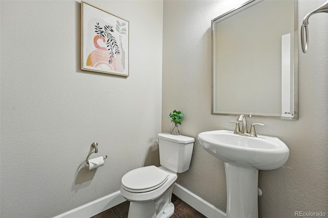 bathroom featuring a sink, toilet, wood finished floors, and baseboards