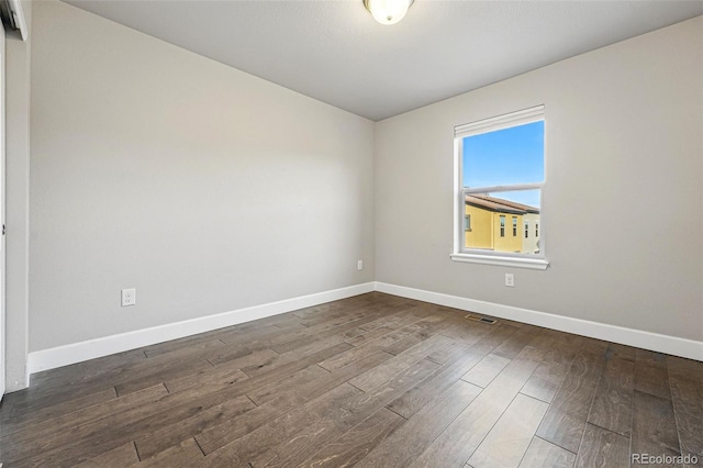 empty room with visible vents, baseboards, and wood finished floors